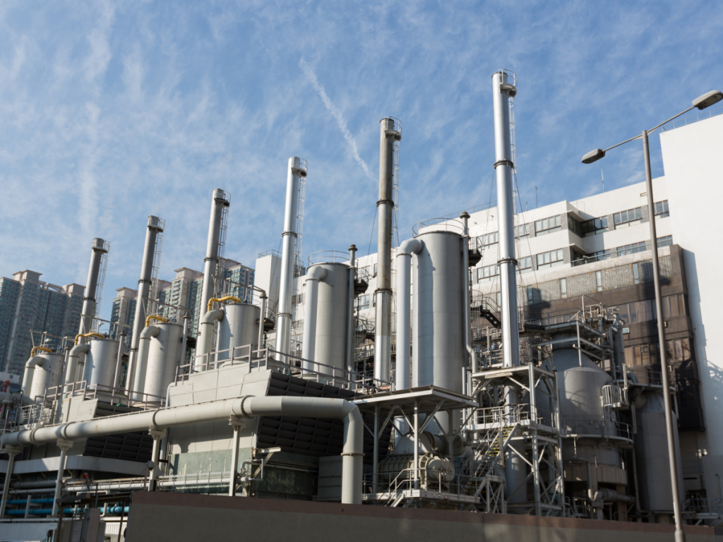 A factory sits under a blue sky smattered with whispy clouds