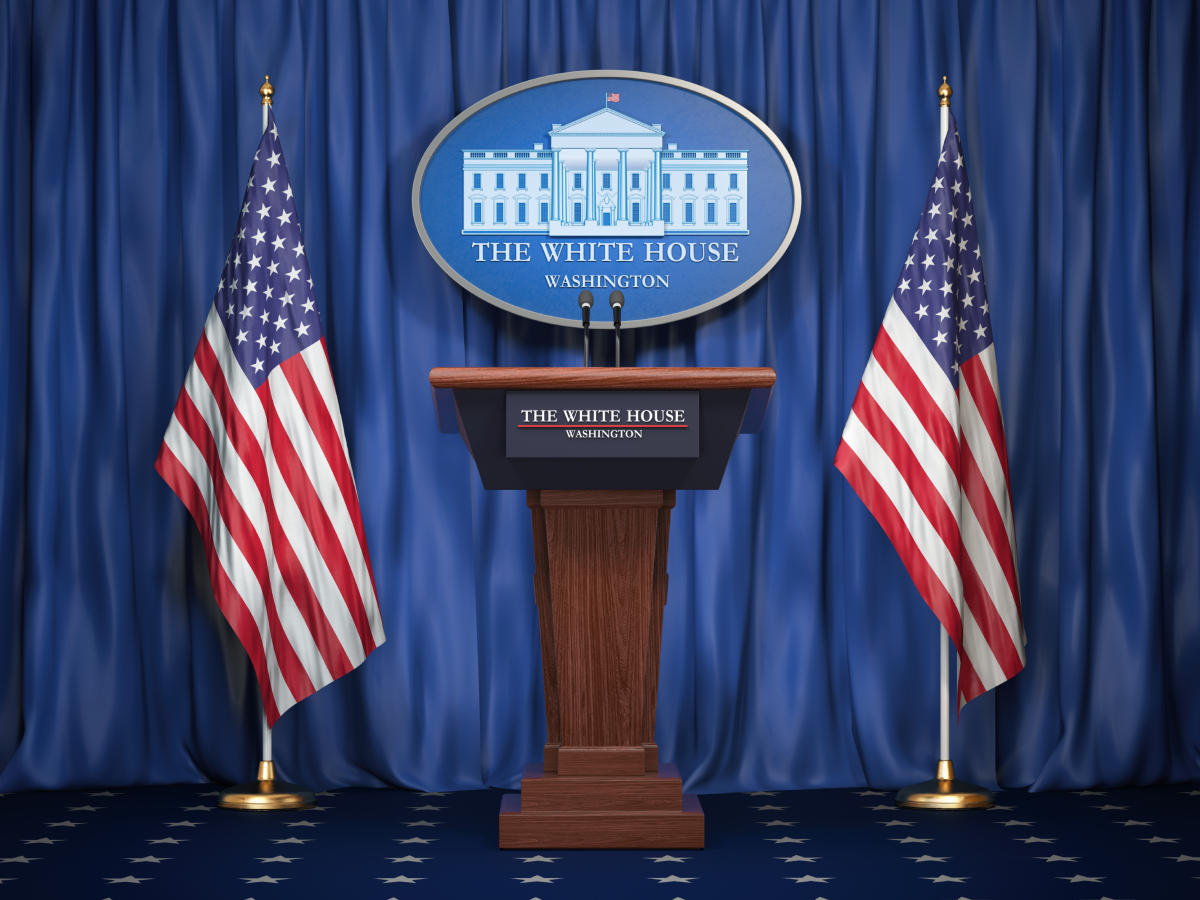 A White House podium flanked by two United States flags