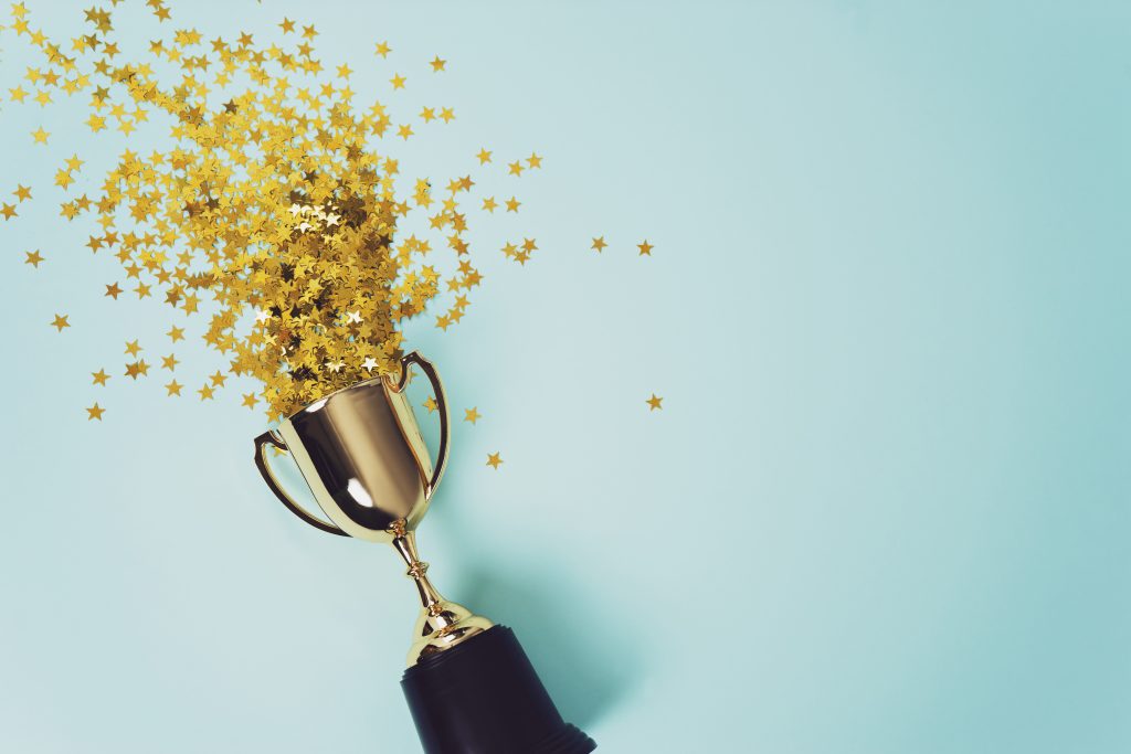 Star-shaped confetti spills out of a golden cup trophy.