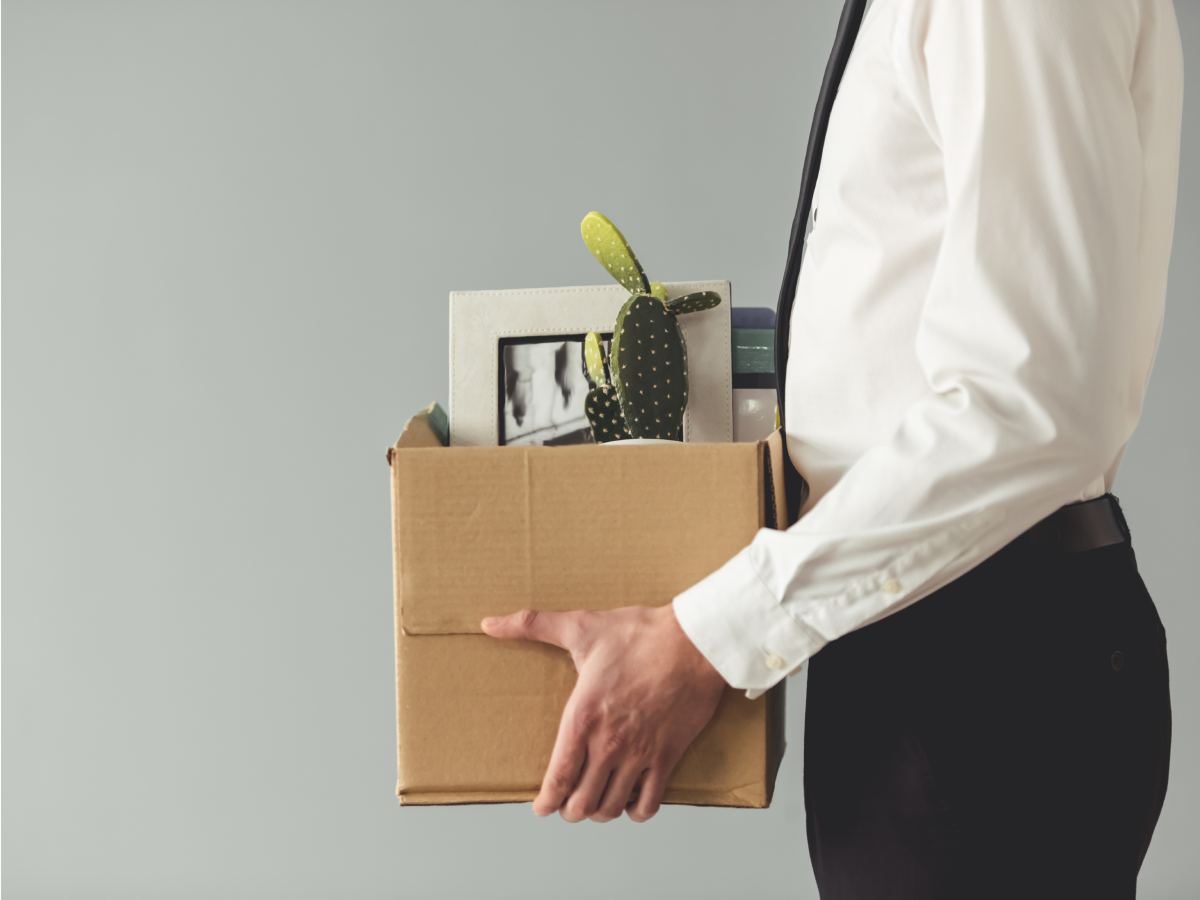 An office worker carries a box of items from their desk