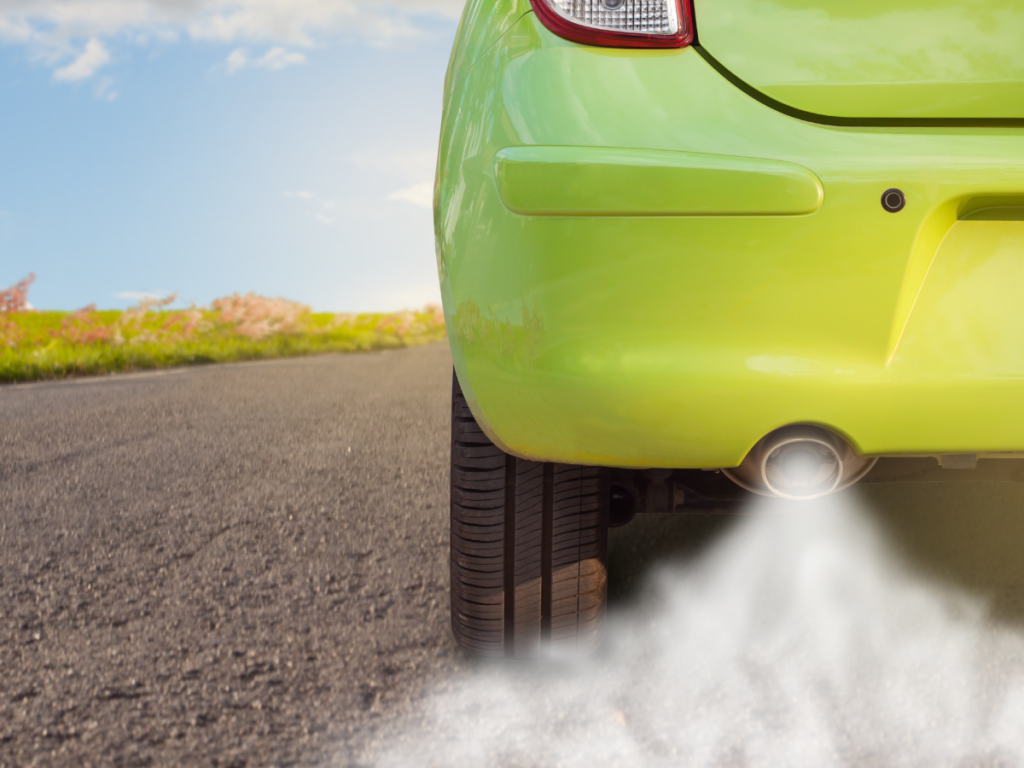 A green car emits a large plume of exhaust fumes