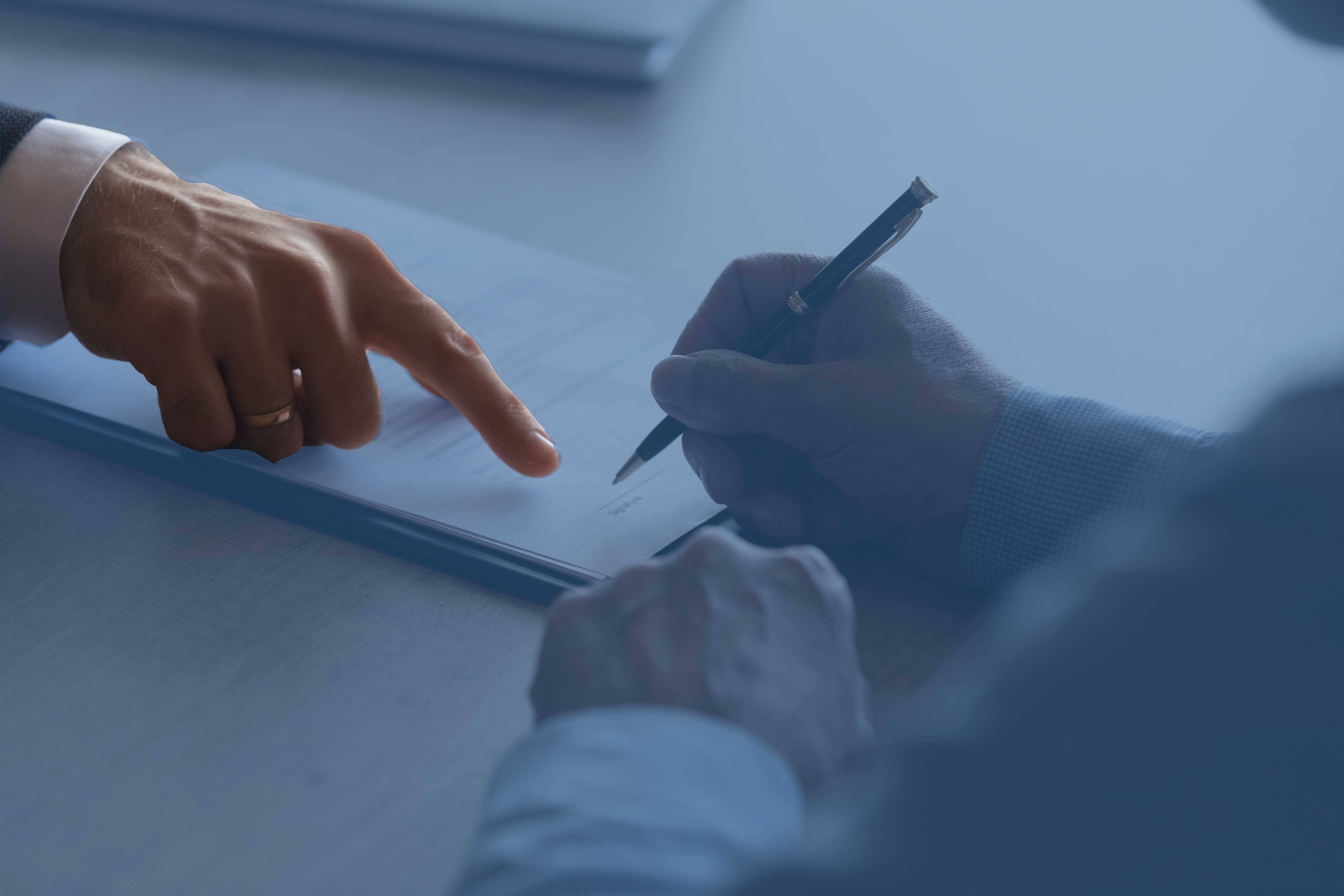 A lawyer shows their client where to sign a contract.