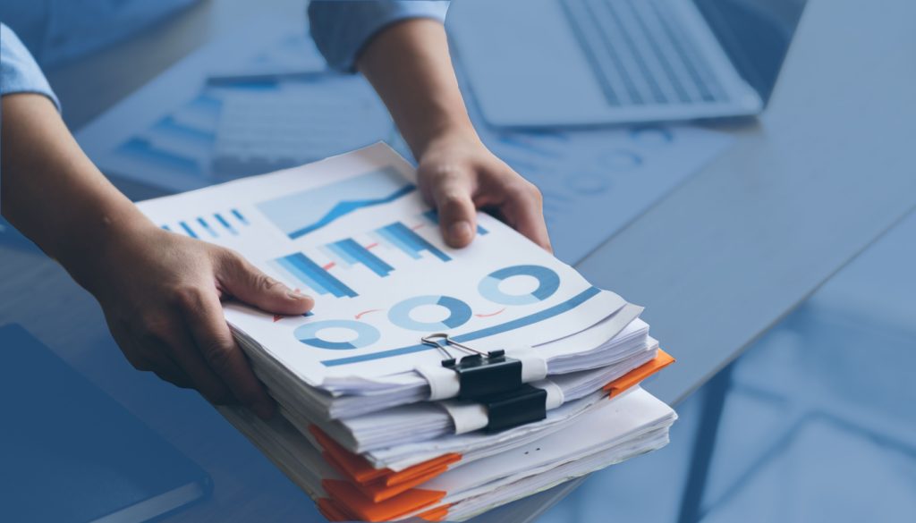 a person places a pile of business documents on a desk