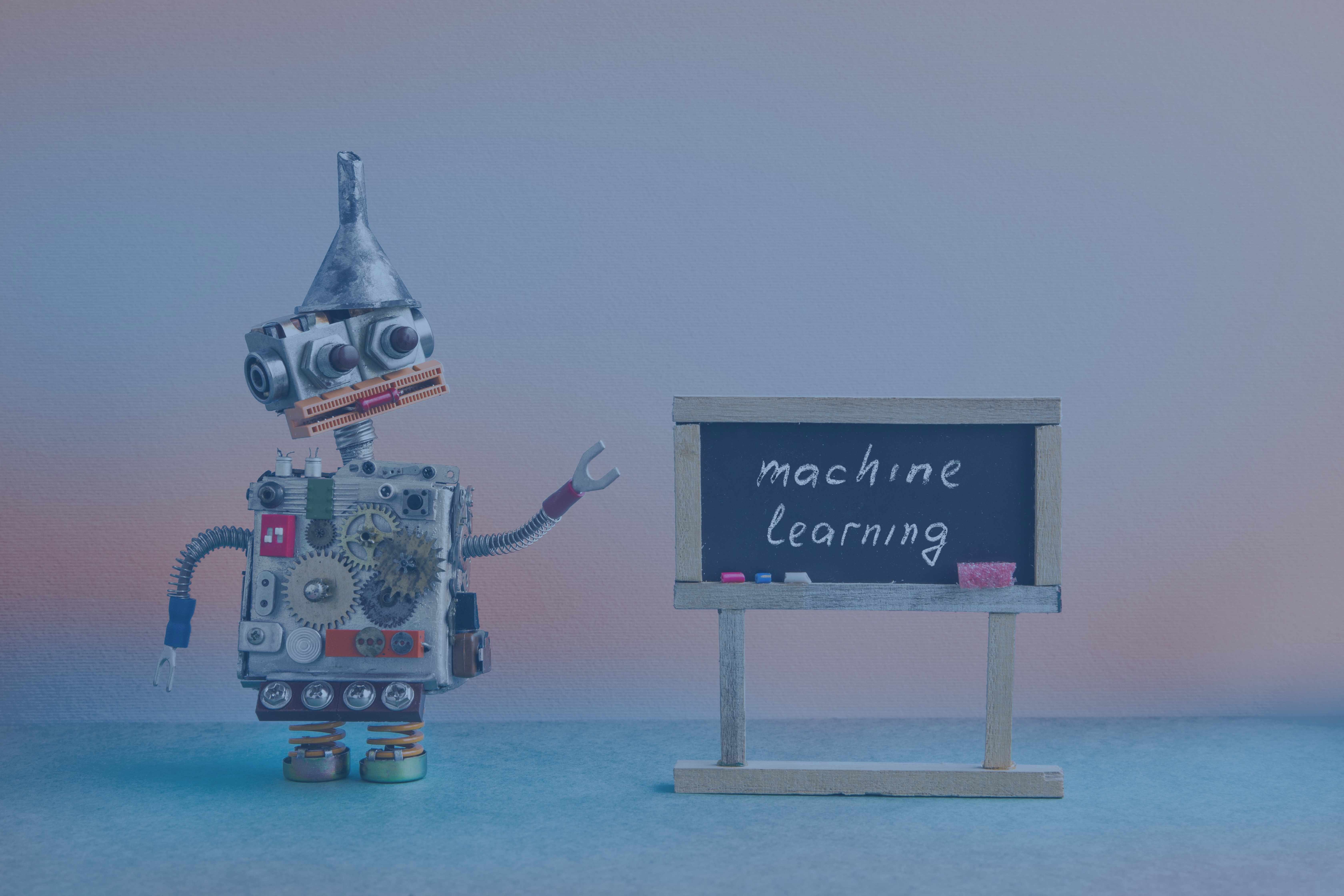 A robot points to a blackboard that reads, ‘machine learning’.