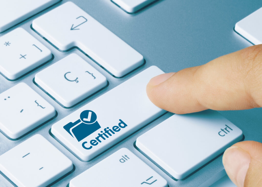 A finger presses a button on a computer keyboard. The button has a folder with a tick and the word ‘certified’ on it. The person pressing the button has plain language certified documents.