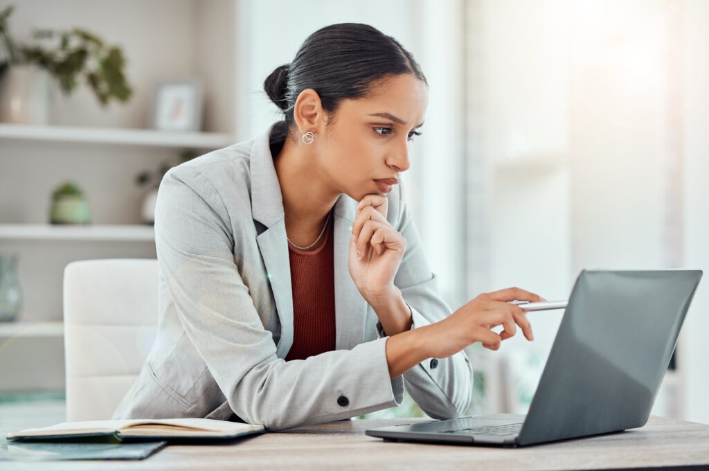 A thoughtful professional carefully reviews a technical document on her laptop. She uses information from our technical writing course to create policies and procedures people can follow easily.