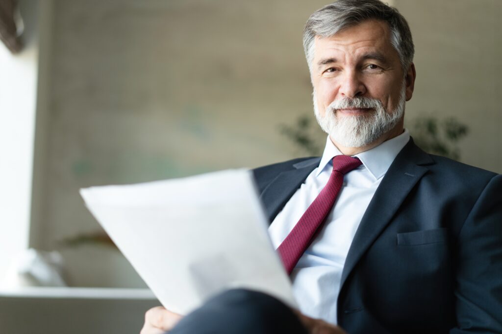 Mature businessman holds document while sitting in office